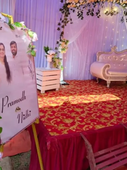 A personalized welcome sign for an engagement, but the floral and drape theme is also perfect for a Mehendi function. The setup includes a white diwan and a backdrop with fairy lights.