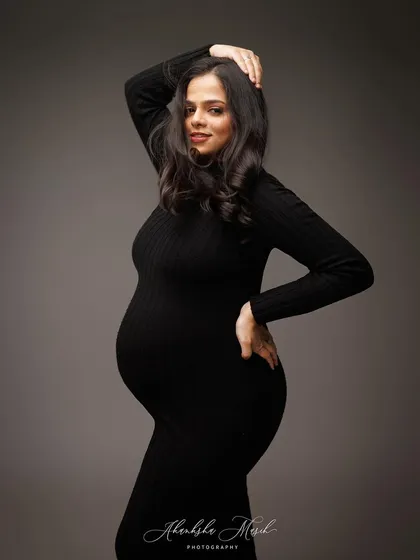 A confident and classic pose in a form-fitting black dress, celebrating the powerful and beautiful silhouette of pregnancy.