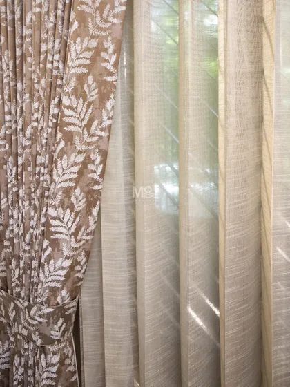 We bring timeless elegance to your windows by layering different textures. Here, a luxurious velvet blend drape with nature-inspired leaf motifs is paired with a lightweight sheer, allowing natural light to filter through while maintaining privacy in this DLF Phase 2 home.