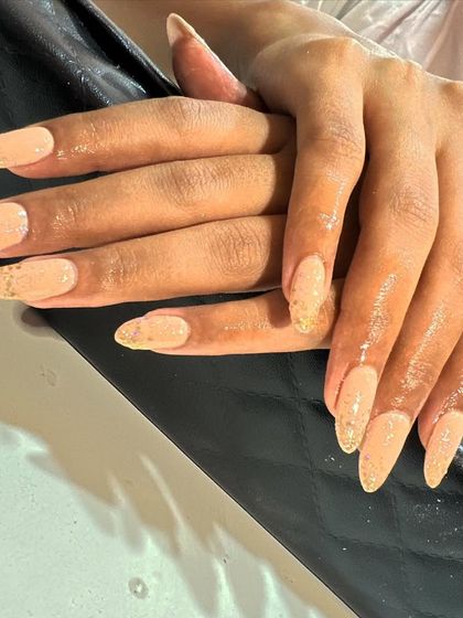 Simple and elegant nude extensions with a touch of gold glitter at the tips for a subtle sparkle.