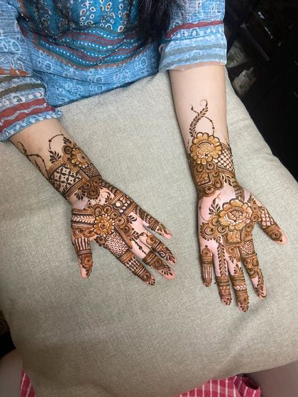 A fusion design that combines bold Arabic flowers on the palm with geometric Indian patterns on the wrist and fingers.