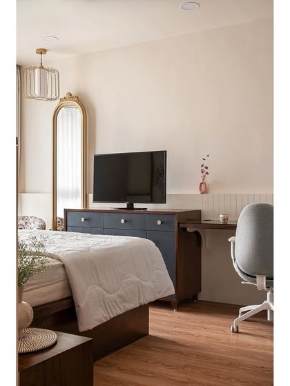 The study and chest of drawers are seamlessly integrated into one unit, providing both workspace and storage. The traditional mirror and warm wood tones enhance the room's functionality and aesthetic appeal.