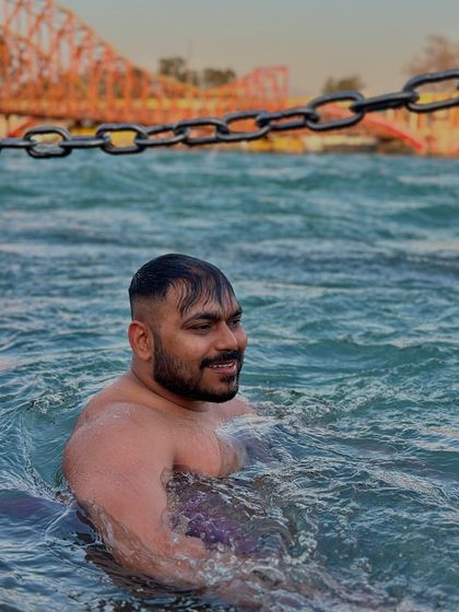 Enjoying the cool, holy waters of the Ganga in Haridwar, with the famous Lakshman Jhula bridge in the distance.