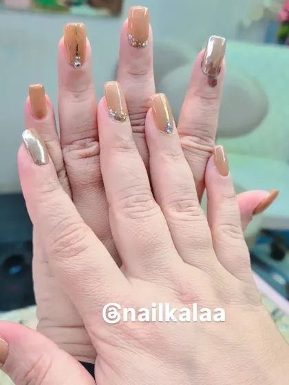 A chic and modern set in shades of nude and caramel. The design includes a mix of solid colors, a metallic gold accent nail, and subtle rhinestone details.