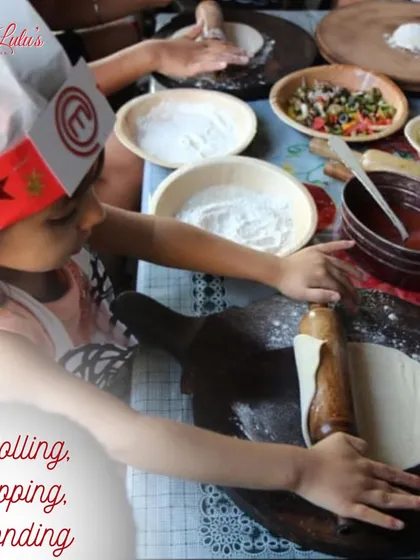 Rolling, topping, and bonding. A young participant carefully rolls out her dough with all the toppings ready to go. It's a great bonding activity for families.