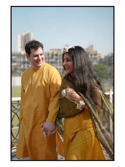 A quiet moment amidst the Haldi fun. The groom from across the oceans, dressed in a traditional kurta, shares a smile with his Odia bride. It’s a beautiful blend of cultures, captured under the warm Mumbai sun.