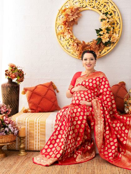 Seated in our cozy, earth-toned setup, this mother-to-be looks serene in her traditional red saree. This portrait celebrates cultural heritage with a modern, artistic touch.