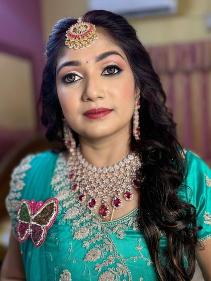 A soft and pretty look by one of my senior stylists. The makeup features light pink and peach tones, complementing the bride's turquoise and ruby-studded outfit.