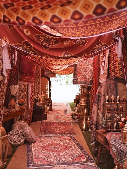 To honor the bride's upbringing in Dubai, we created a 'Grand Souk' entrance for her Mehendi. Guests walked through a passage layered with rich carpets, traditional fabrics, and glowing lanterns, instantly evoking the feel of a timeless market.