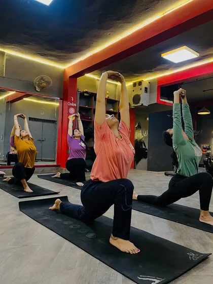 The class moves into Anjaneyasana (Low Lunge), a deep stretch for the hips and quadriceps. The synchronized movement creates a powerful collective energy.