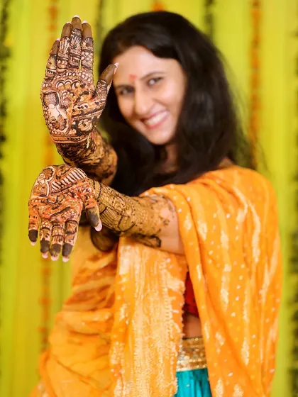 A joyful shot of the bride showing off her intricate henna design. Her smile is infectious and captures the spirit of the Mehndi ceremony.