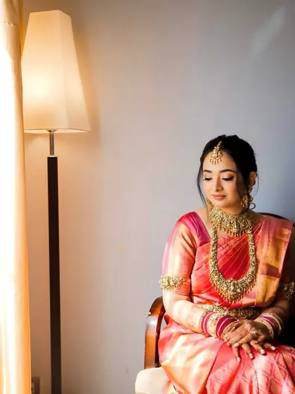 A quiet moment of reflection before the ceremony. The lighting highlights her radiant skin and the intricate gold temple jewellery.