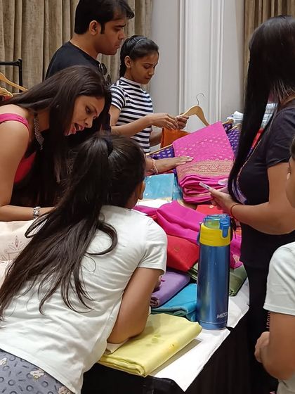 A group of shoppers gathered around a stall, examining colourful textiles and fabrics.