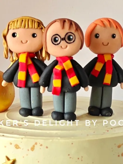 A detailed look at the hand-sculpted fondant toppers of Harry, Hermione, and Ron, complete with their Gryffindor scarves.