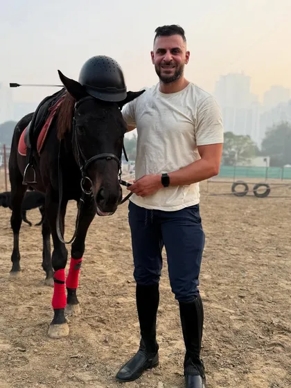 A playful moment captured during a solo photoshoot, with the rider placing his helmet on the horse's head. Our horses are patient and good-natured.