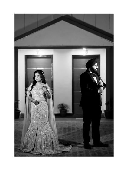 A stylish black and white portrait of the couple on their engagement day. The composition creates a sense of modern elegance and drama, focusing on their fashionable attire and confident poses.