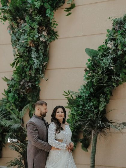 A classic portrait from a ring ceremony, with the couple framed by beautiful green floral decorations, adding a touch of nature to the event.