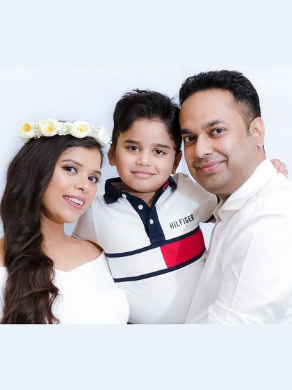A happy family portrait with their young son. The mother's floral crown adds a soft, celebratory touch to this bright and cheerful at-home studio photo.