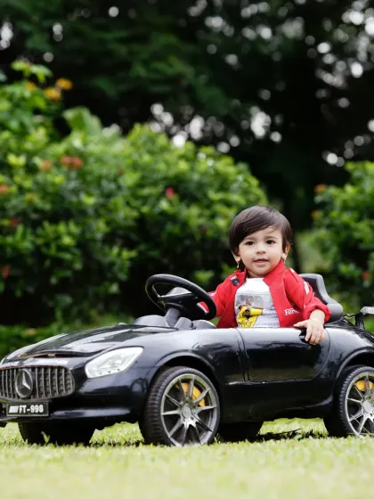 A fun and stylish outdoor pre-birthday shoot featuring a mini Mercedes toy car. These prop-based shoots are a great way to capture your child's personality in a playful and dynamic setting.