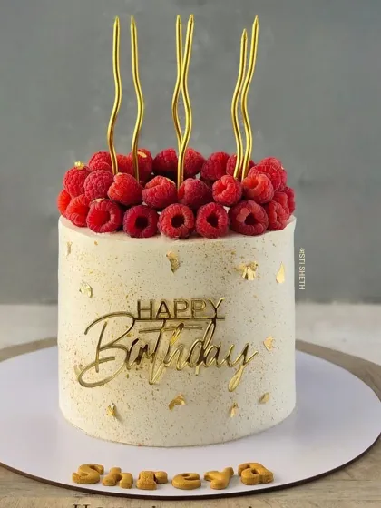 An elegant cake topped with a crown of fresh raspberries and gold accents, a recreation of a client's Pinterest inspiration.