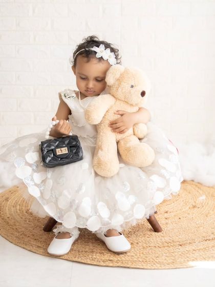 A tender moment as she hugs her teddy bear. Props like favorite toys can help children feel comfortable during the shoot.