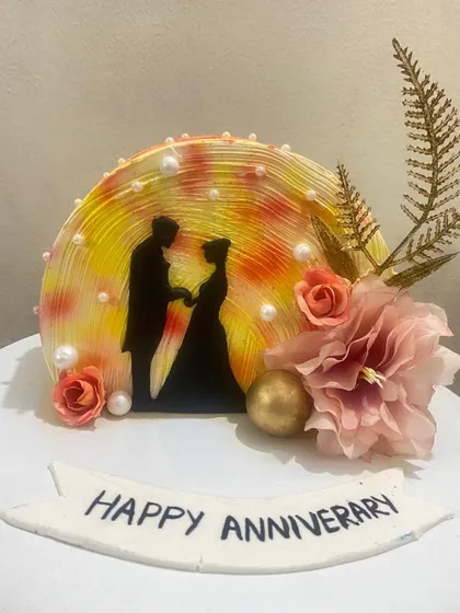 A romantic anniversary cake with a silhouette of a couple against a warm, glowing background.