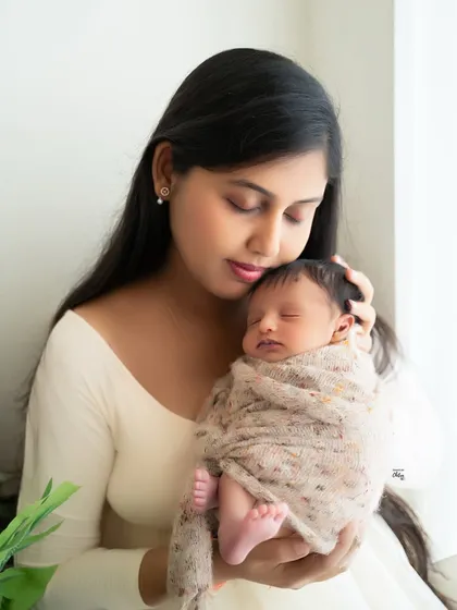 A mother cradling her newborn by the window. This image uses beautiful natural light to create a soft, glowing portrait that feels both intimate and serene.
