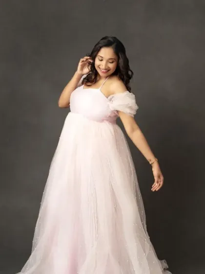 Soft, sweet, and simply beautiful. This light pink off-the-shoulder tulle gown offers a classic princess look for a gentle and romantic maternity photoshoot.