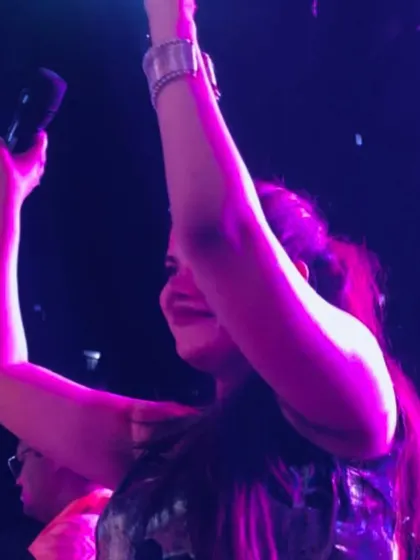 Arms up in celebration during a vibrant Dandiya night. The energy under the purple lights was electric.