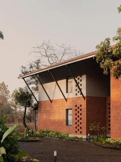 An exterior view of Maison Rouge, a family home built on ancestral land in the Konkan belt. We balanced contemporary planning with vernacular building traditions, using locally sourced laterite stone to create a structure that feels rooted in its place and history.