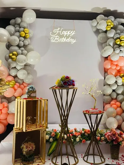 We also design elegant and sophisticated birthday setups for any age. This arrangement combines modern metallic pedestals, lush balloon garlands in peach and grey, dried pampas grass, and a neon "Happy Birthday" sign for a chic and stylish celebration.