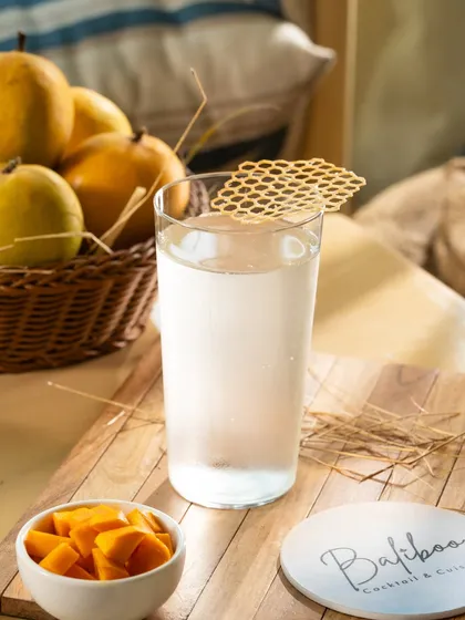 A clear, refreshing drink with a honeycomb garnish. The natural light and bright styling make this perfect for a summer menu.