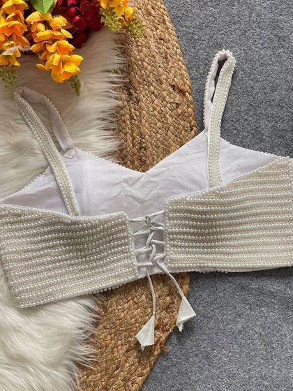 The back of the white pearl blouse, showing the delicate tie-up detail with tassels.