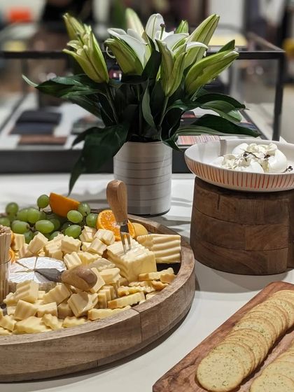 A full view of the cheese and cracker station at the Paul Smith event. The setup includes a large cheese board, fresh burrata, and crackers, all elegantly arranged.