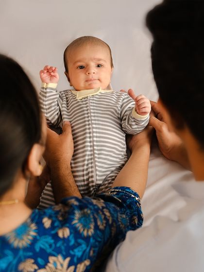 A unique perspective of parents holding their baby, who looks curiously at the camera. This candid style of family photography captures the real, in-between moments of connection.