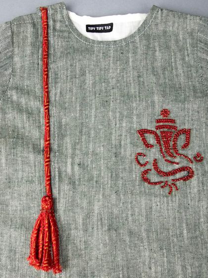 A close-up of the red Ganesha embroidery and tassel on a grey kids' kurta.