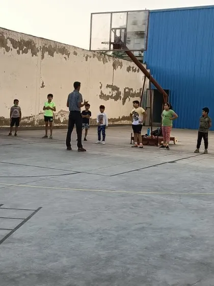 I am explaining a drill to a group of young basketball players. My coaching method involves direct instruction and breaking down plays to help build a strong foundation in the sport.