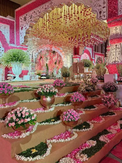 An enchanting symphony of blooms and traditional grandeur. The steps leading to the mandap are adorned with floral arrangements, creating a path of beauty for the couple. 🌸❤️