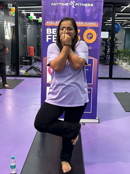 Even with a smile, this participant shows the determination it takes to hold a challenging yoga pose. It's all about progress, not perfection.
