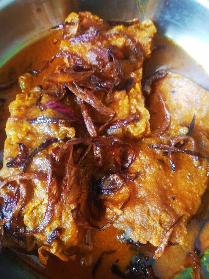 This is Katlar Kalia, a rich and aromatic fish curry often served at Bengali weddings, or 'biyebaris'. The fried onions on top add a wonderful texture and sweetness to the spicy gravy.