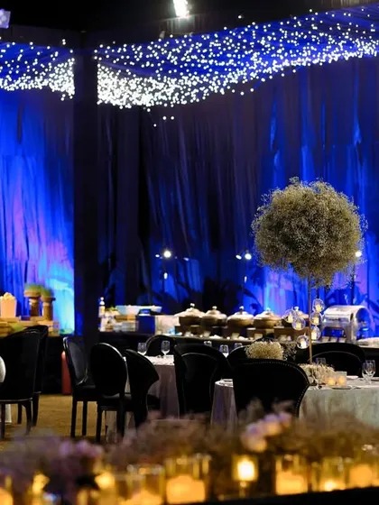 The dining area under a canopy of fairy lights, with a large illuminated moon prop and tall baby's breath centerpieces creating a dreamy, celestial atmosphere.