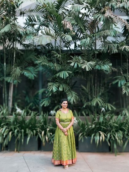 A wide shot showcasing the bride's beautiful green outfit against a backdrop of tropical plants.