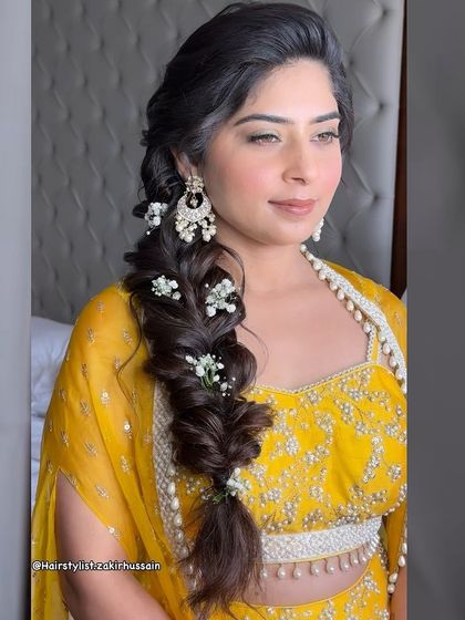 The same side-swept fishtail braid, now adorned with delicate baby's breath. This shows how easily the style can be transformed for a more romantic, bridal feel.