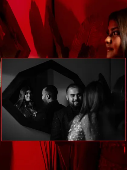 A creative black and white reflection shot of a couple in a mirror, surrounded by a bold red frame, adding an artistic touch to their party look.
