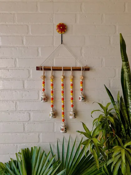 Our 'Beads and Bells' handmade wall hanging, shown here in the 'Sunflower' variant with yellow and orange beads. It comes with a 14-inch dowel and a ceramic wall hook, making it a complete decor piece.