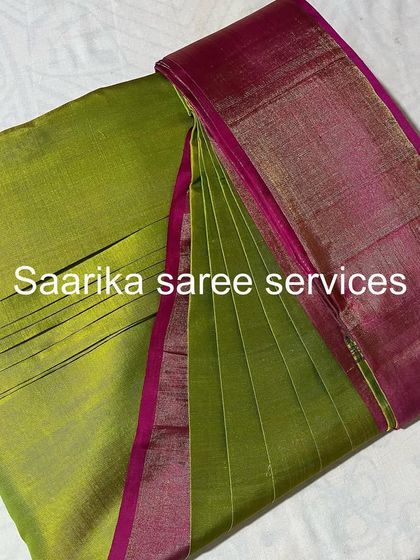 A lime green saree with a pink border, pleated and ready. This vibrant saree is perfect for a summer event.