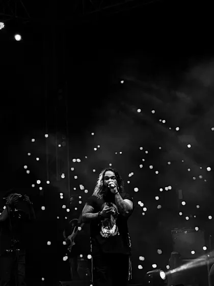 A powerful black and white image of our frontman commanding the stage, with the crowd's phone lights twinkling like stars.