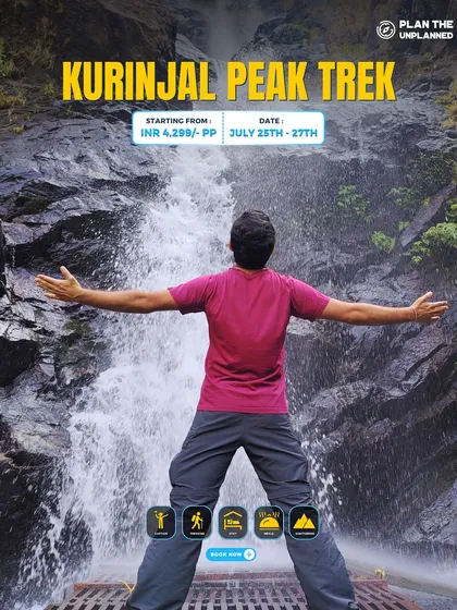A trekker stands with arms open in front of a waterfall on the Kurinjal Peak trek, located inside the Kudremukh National Park.