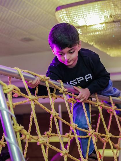 Concentration and determination as a young adventurer climbs across the net bridge. It's a fantastic physical challenge for active kids.