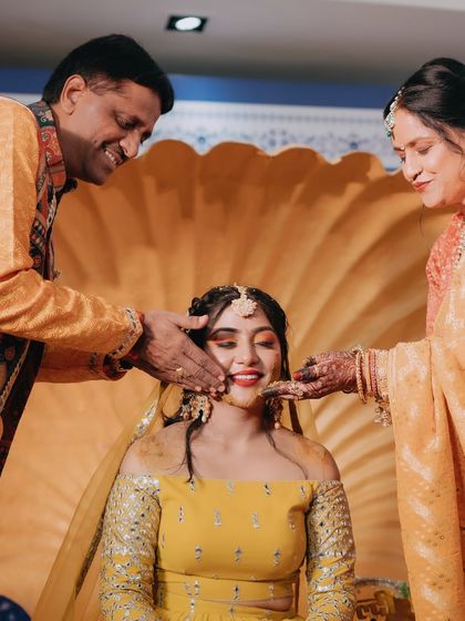 The bride receives blessings from her parents as they apply haldi, a traditional and emotional moment.